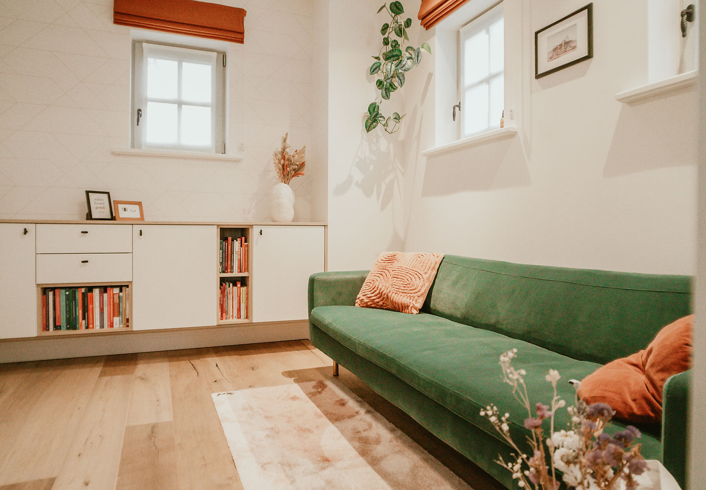 De praktijkruimte met groene zetel, planten en boekenkast